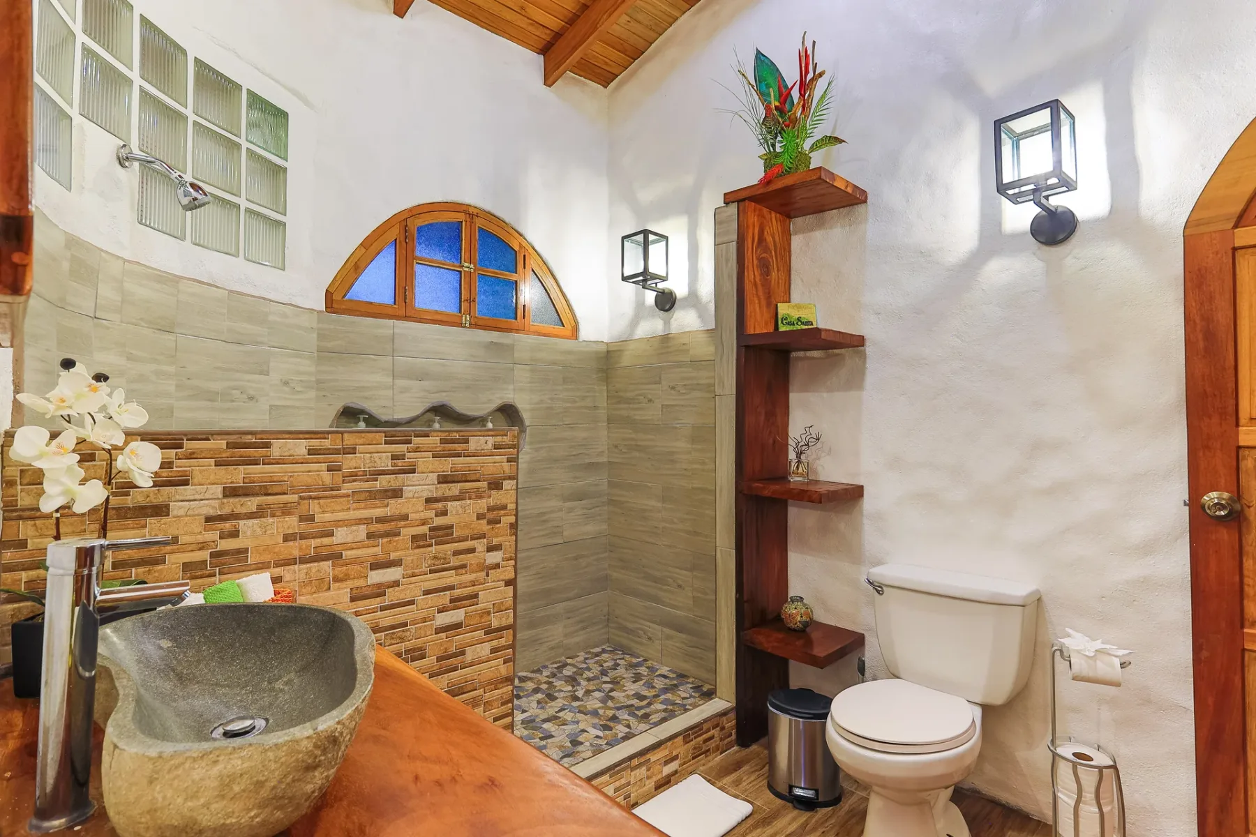 A bathroom with a stone sink, tiled shower area, and toilet.
