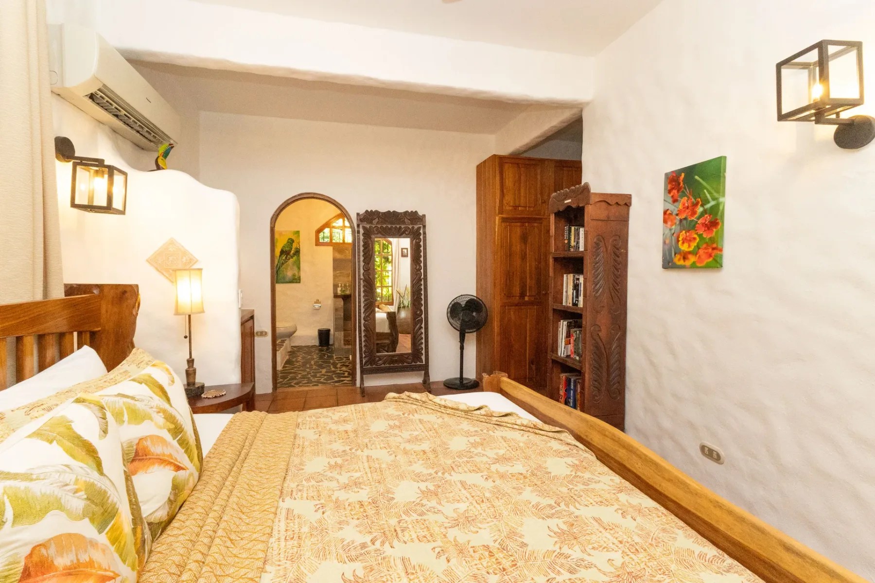 A bedroom with a bed, wooden bookcase, and arched doorway.
