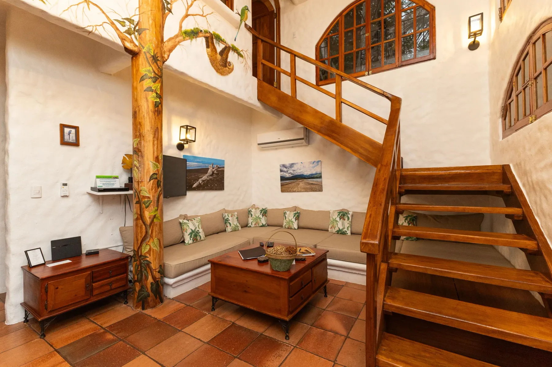 A living room with built-in seating beneath a wooden staircase.