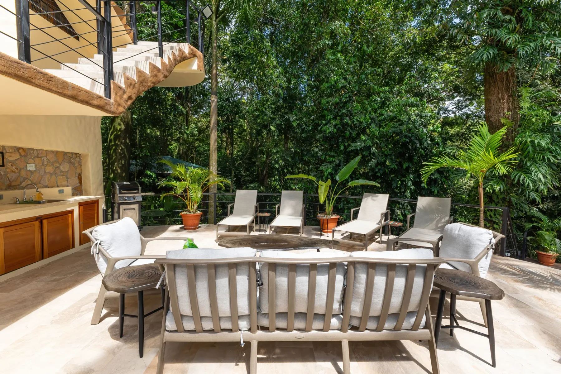 An outdoor patio with seating, potted plants, and a built-in counter beside the house.
