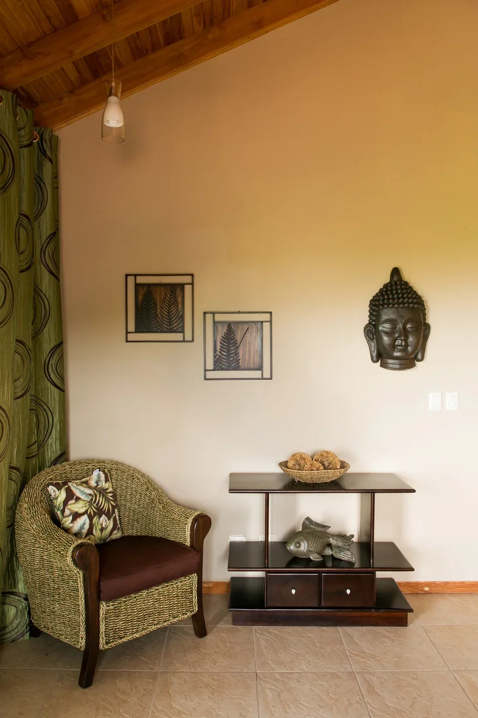 Una habitación decorada con calidez, un sillón tejido y cuadros en la pared.