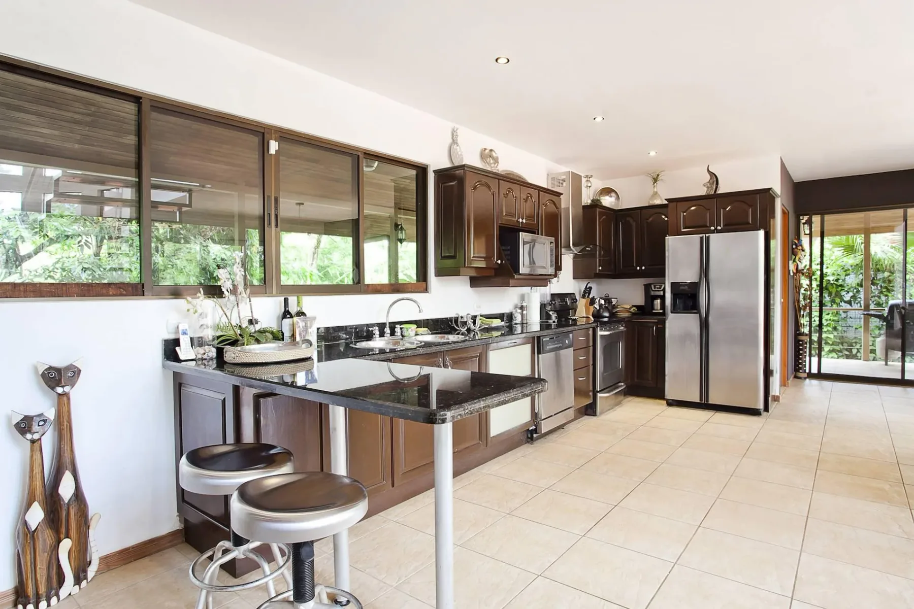 Una cocina luminosa con gabinetes oscuros, una isla central y electrodomésticos de acero inoxidable.