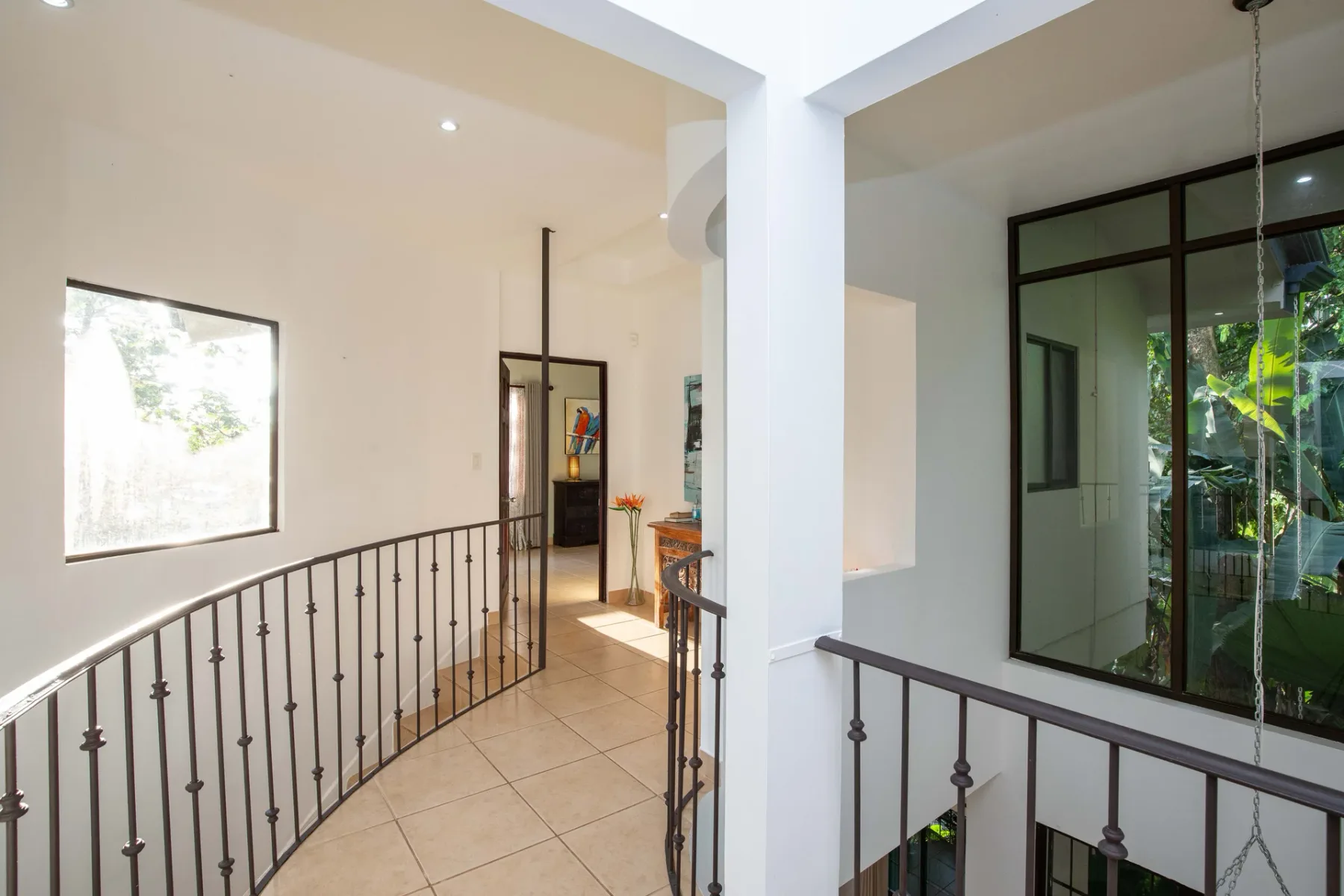 A bright interior landing with a tiled floor and dark metal railing.