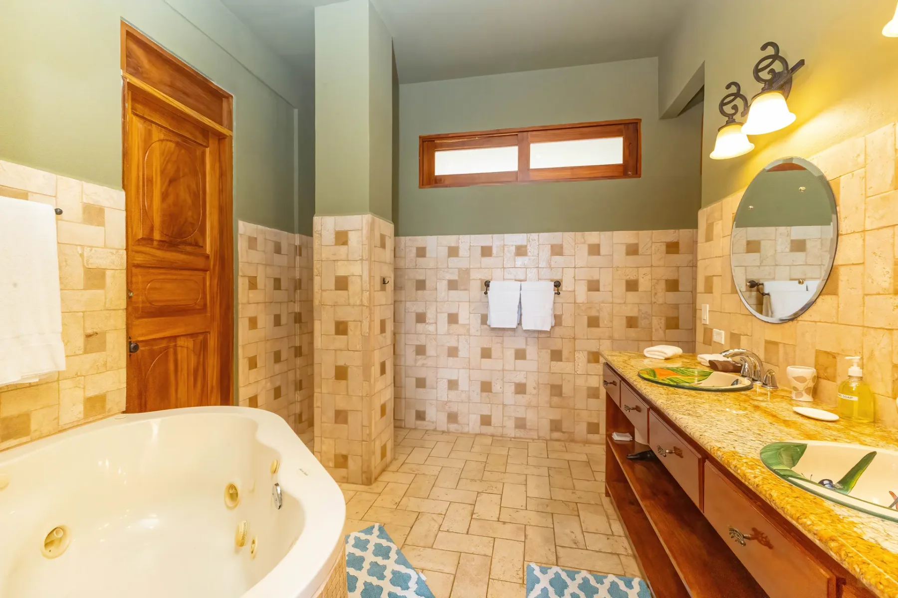 Un baño con bañera de hidromasaje, lavabo y una ventana horizontal alta.