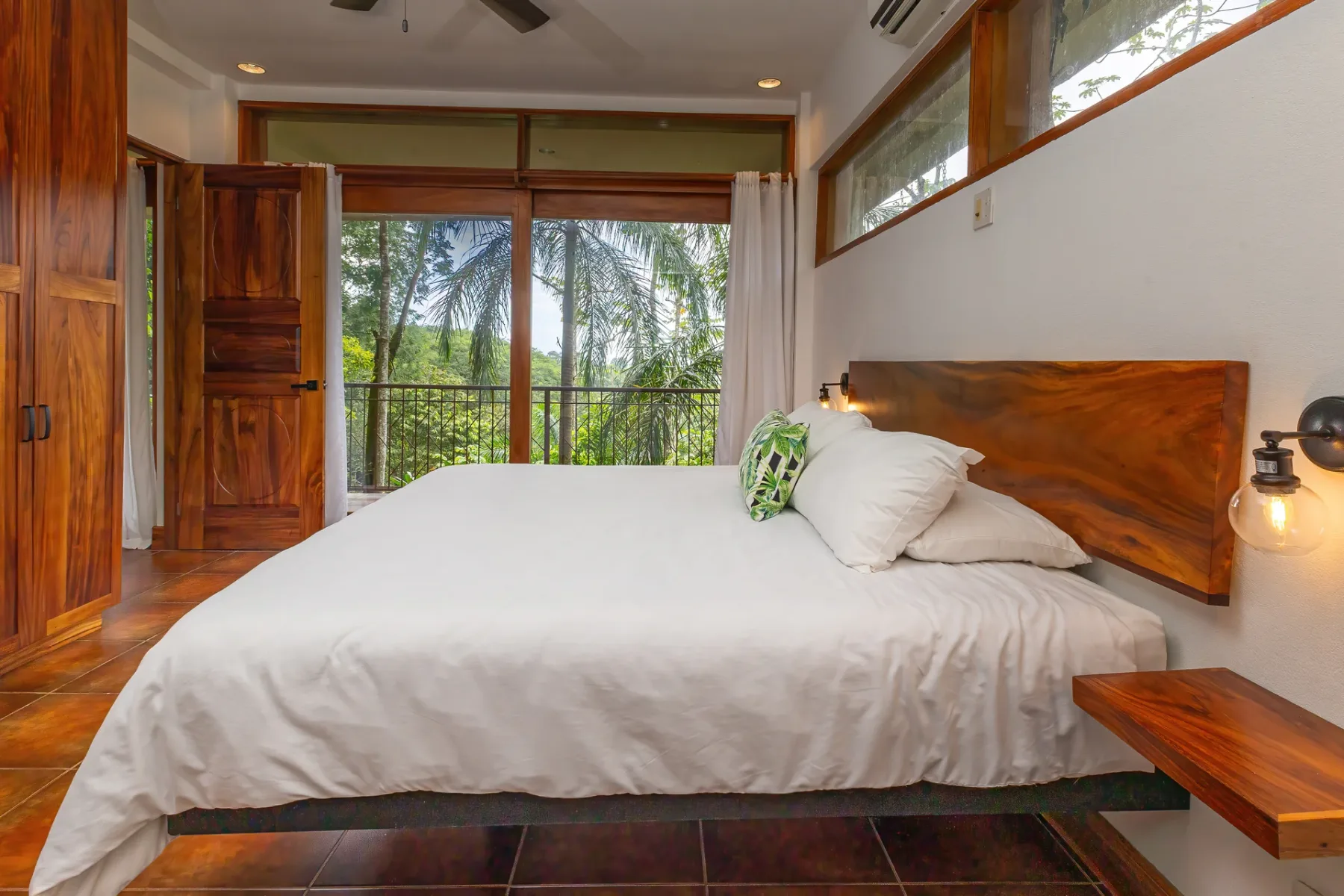 Un dormitorio con una cama frente a puertas de vidrio que dan a un balcón.