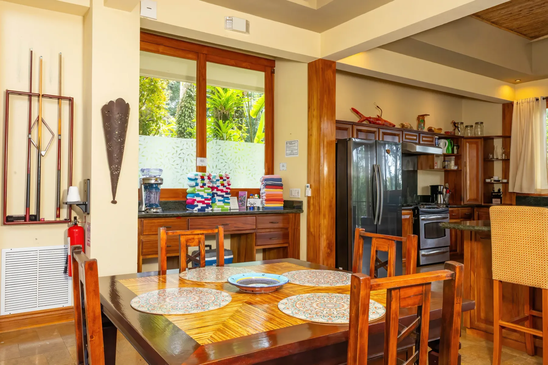 Un comedor se abre a la cocina, con una mesa de madera junto a las ventanas.