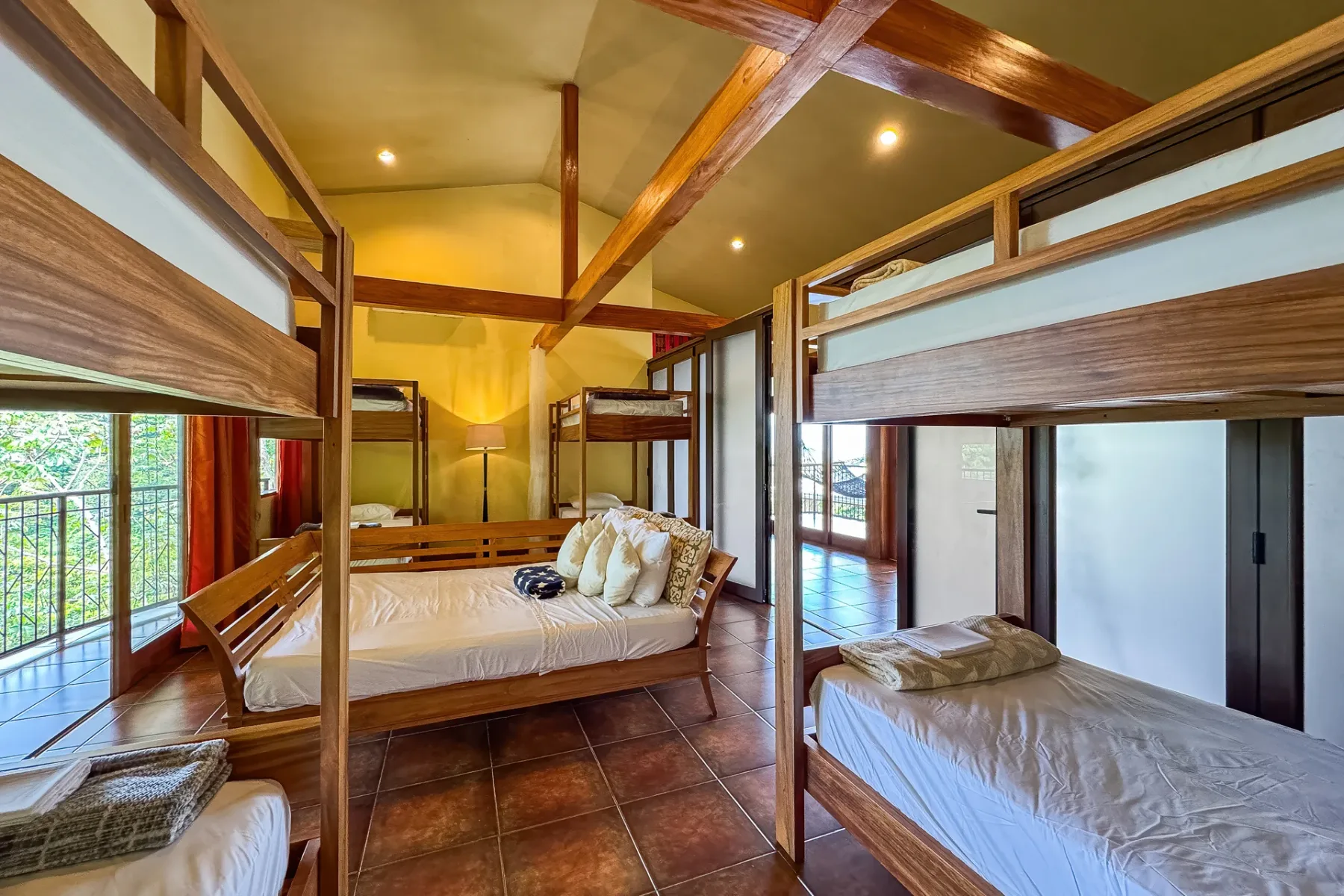 Dormitorio luminoso con varias camas y vigas de madera expuestas.