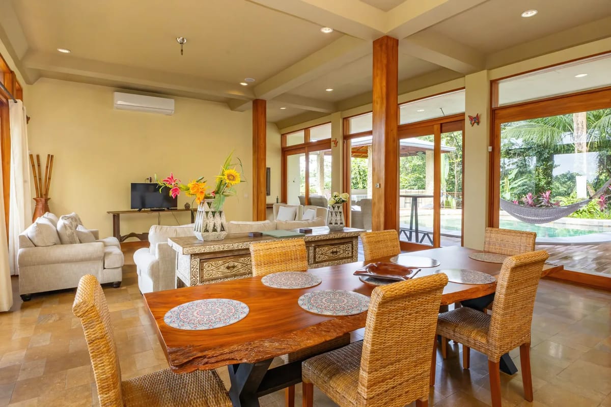 The Rainforest Estate · 5. This expansive living and dining area features natural wood accents, comfortable seating, and floor-to-ceiling glass doors that open to a tropical pool deck and lush rainforest.