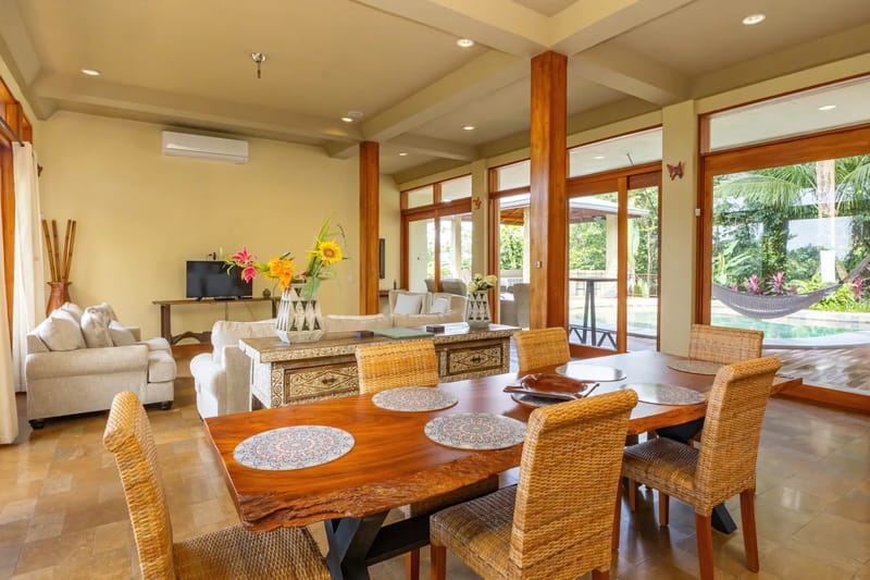 The Rainforest Estate · 5. This expansive living and dining area features natural wood accents, comfortable seating, and floor-to-ceiling glass doors that open to a tropical pool deck and lush rainforest.