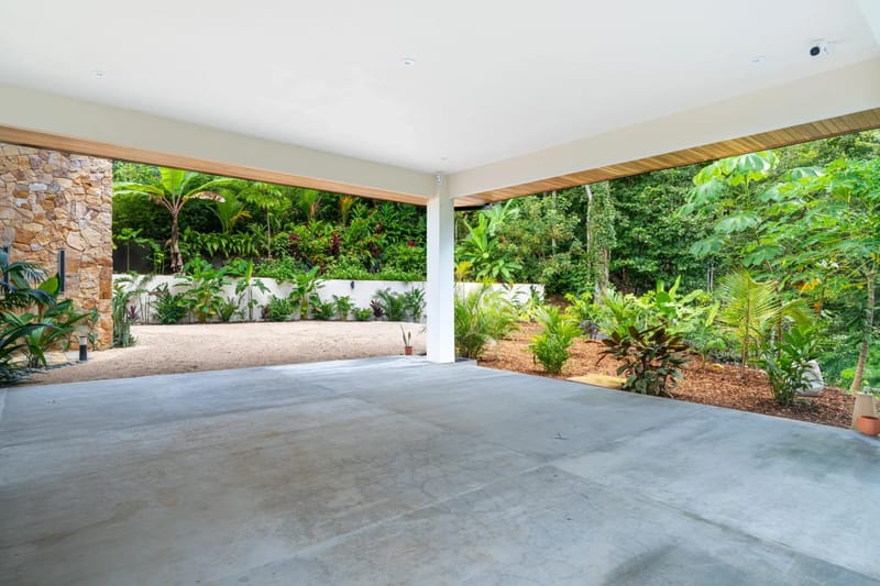 Villa del Cielo · 17. This open-air covered concrete parking area features a stone wall and timber-accented ceiling, with direct views into lush tropical gardens.