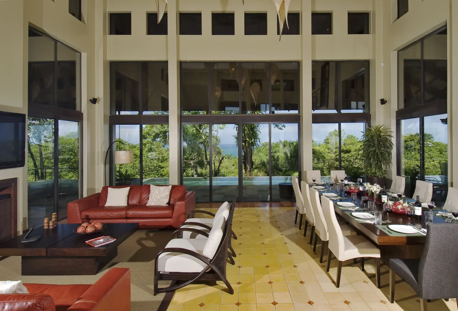A spacious dining and sitting area opens onto floor-to-ceiling windows overlooking greenery.