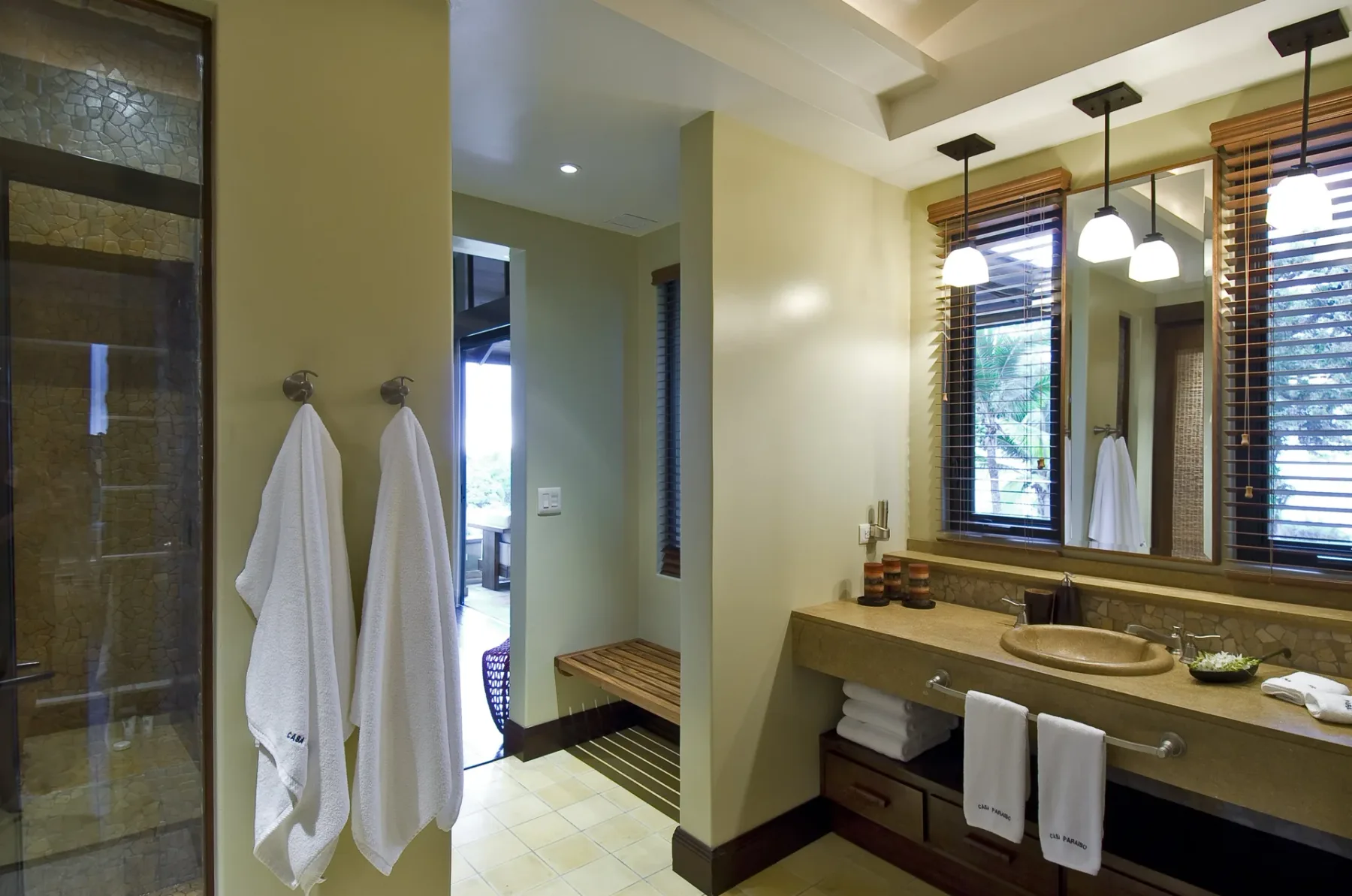 A bathroom vanity with a sink, mirror, and hanging towels.