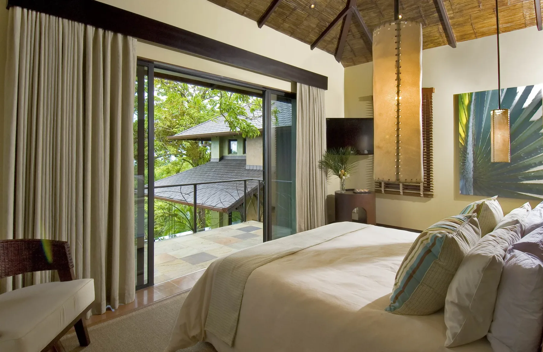 A bedroom with a large bed beside an open sliding glass door.