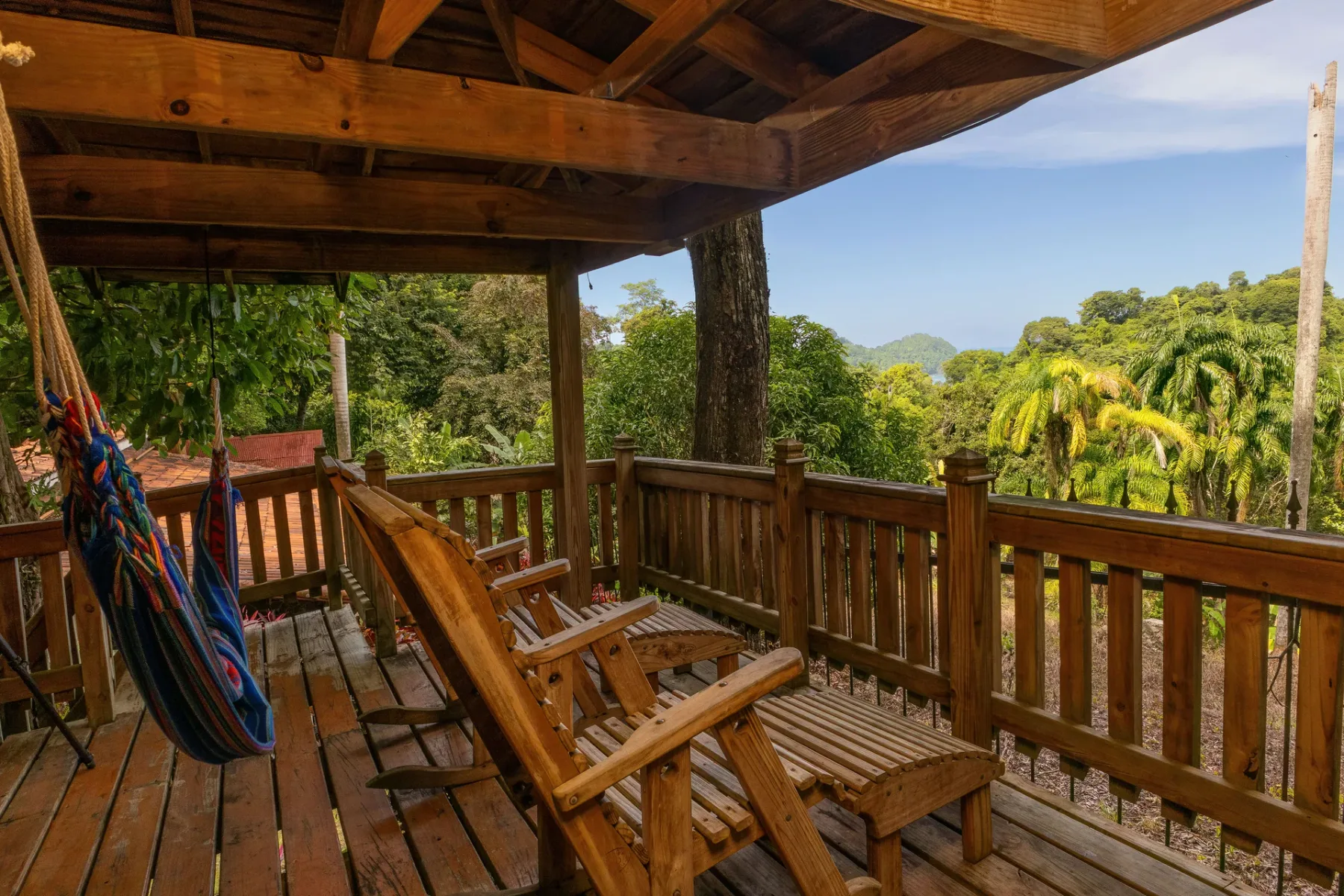 Una terraza cubierta de madera con asientos da a un paisaje verde y montañoso.