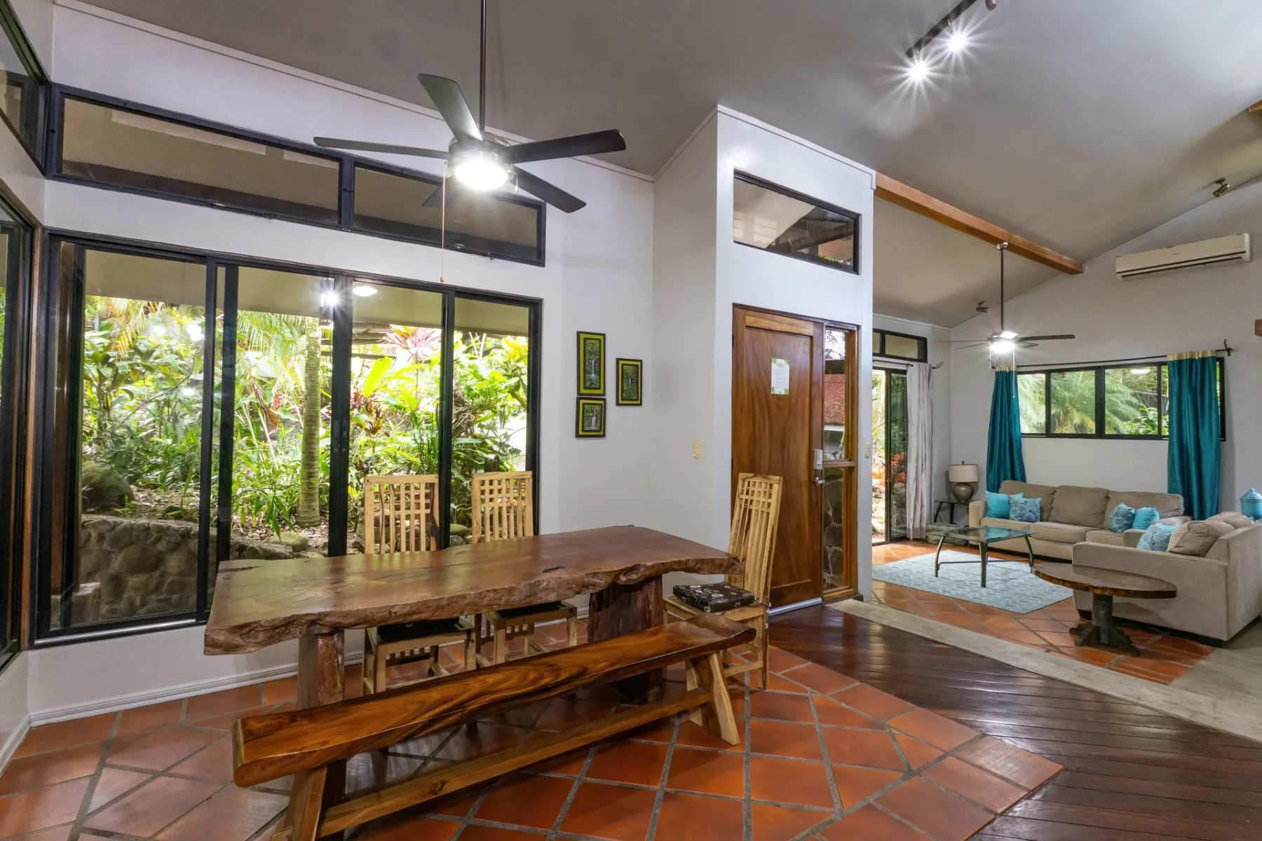 Un espacio abierto de sala y comedor con asientos de madera y ventanas grandes.