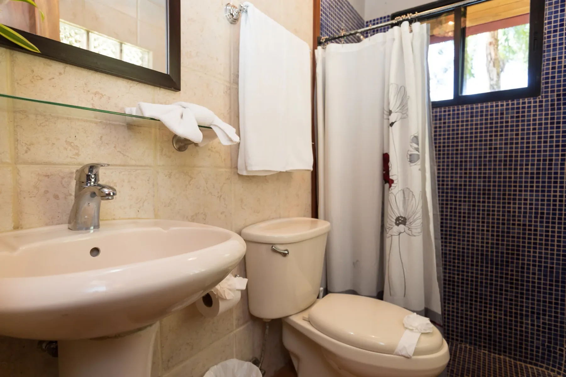 Un baño con lavabo, inodoro y cortina de ducha junto a una pared de azulejos.
