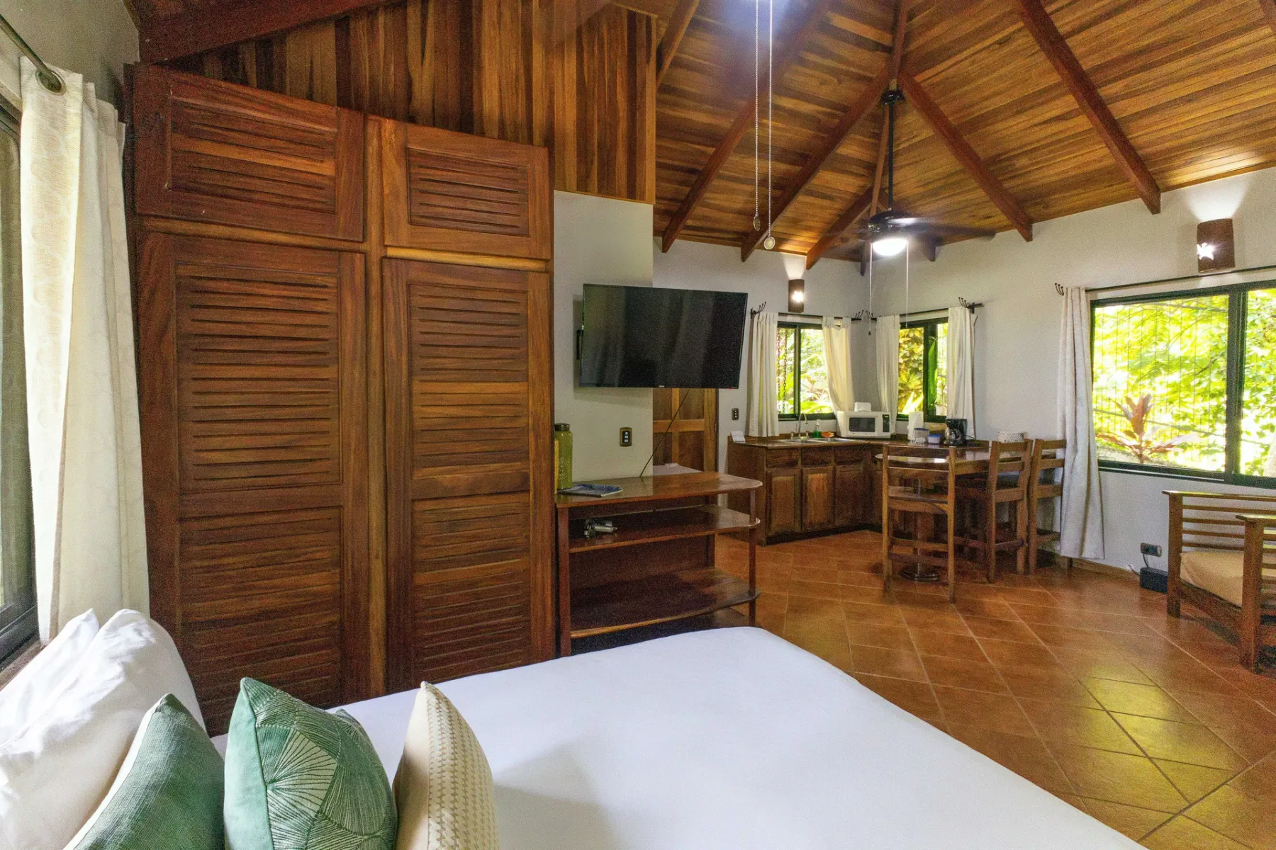 Un dormitorio revestido de madera se abre a un comedor con mesa y sillas.