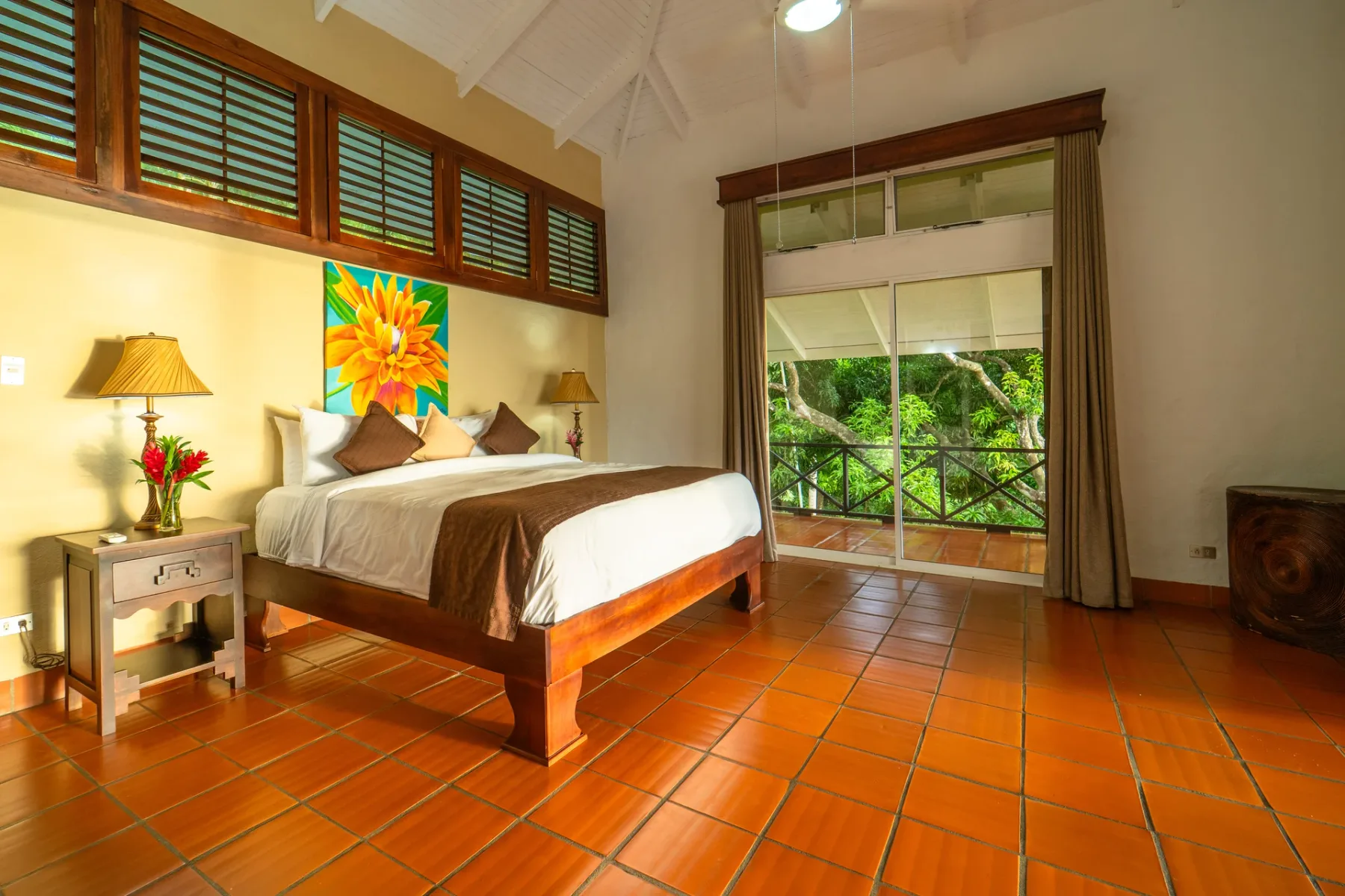 Dormitorio con una cama junto a una gran ventana con vistas a la vegetación.