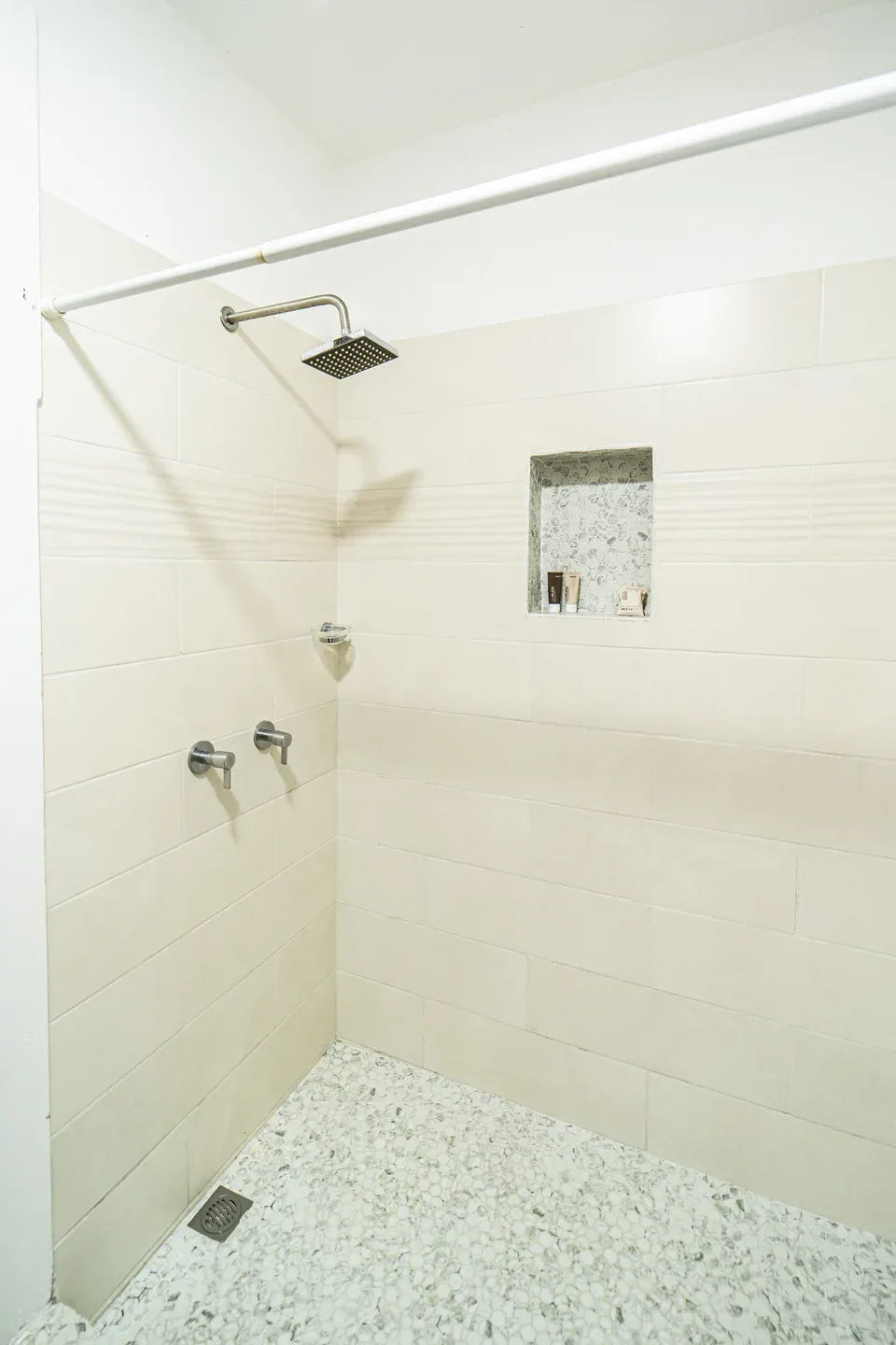 Una ducha alicatada con rociador de pared y un nicho empotrado.