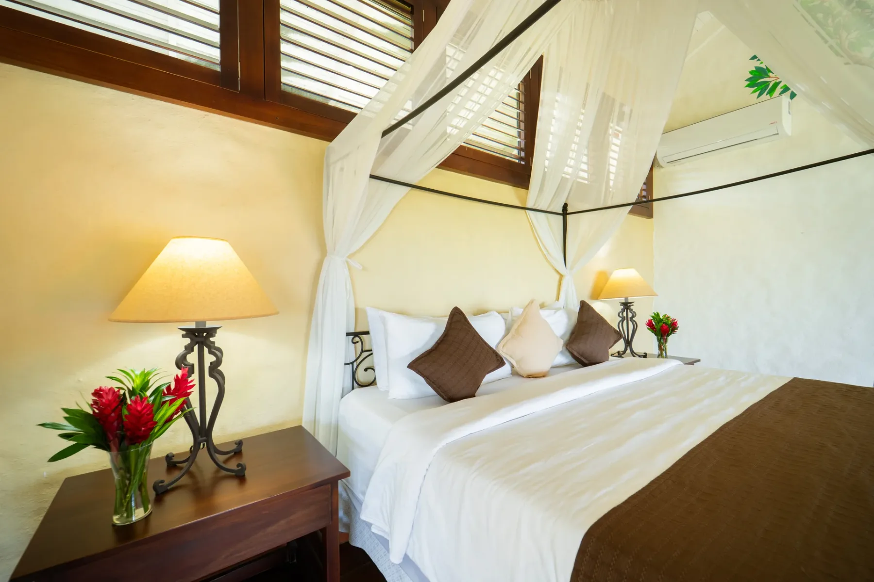 Un dormitorio con cama con dosel, ropa de cama blanca y lámparas de noche.