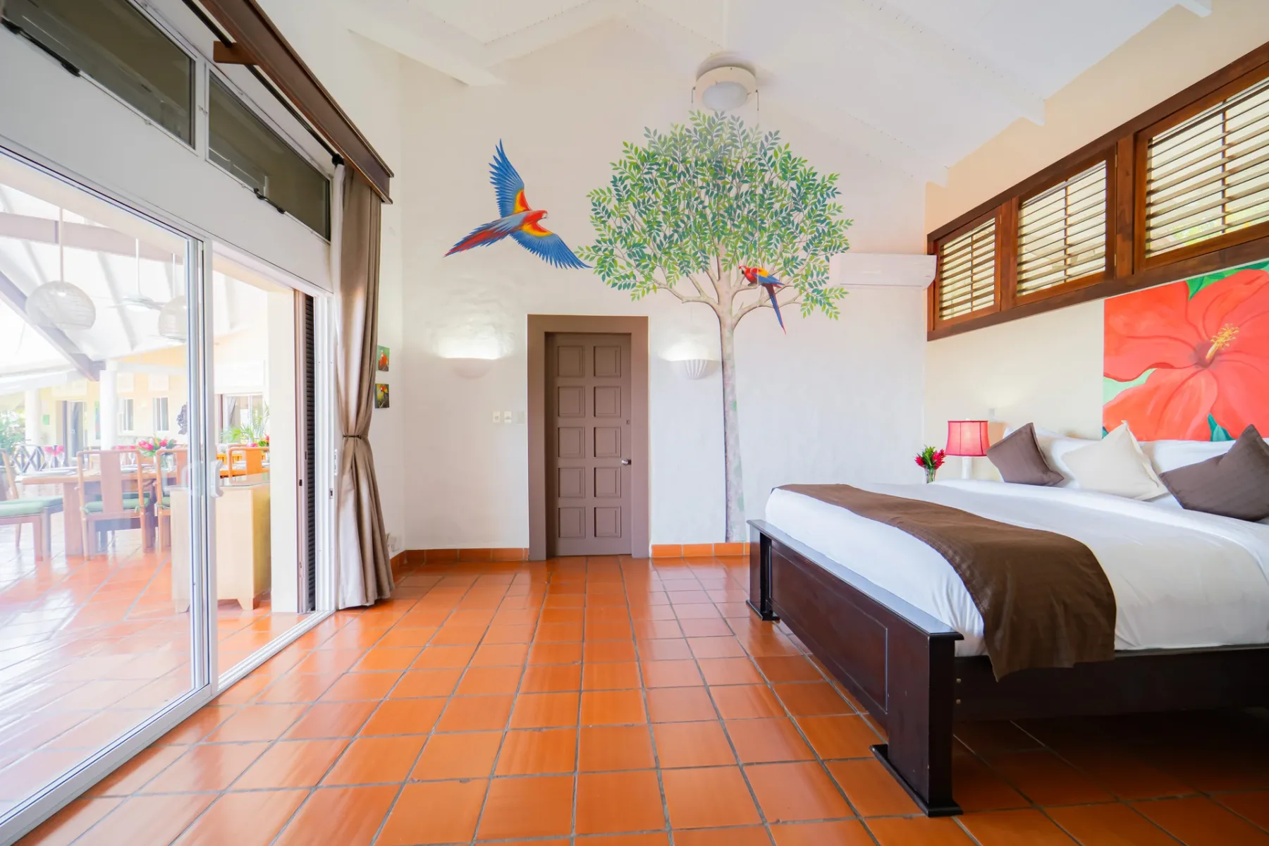 Un dormitorio con una cama grande, arte colorido en la pared y una puerta corrediza de vidrio.