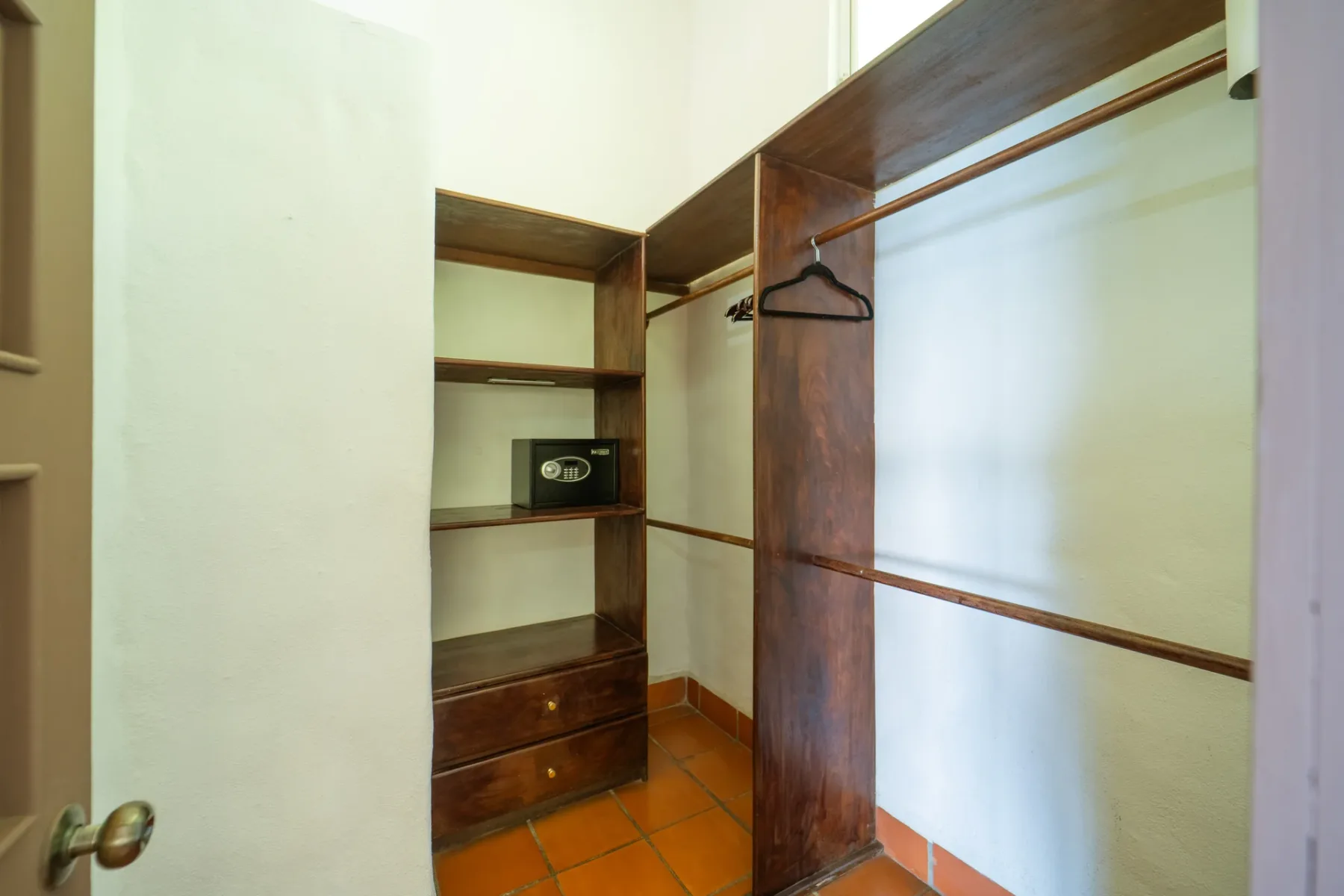 Un vestidor con estantes de madera y espacio para colgar ropa.
