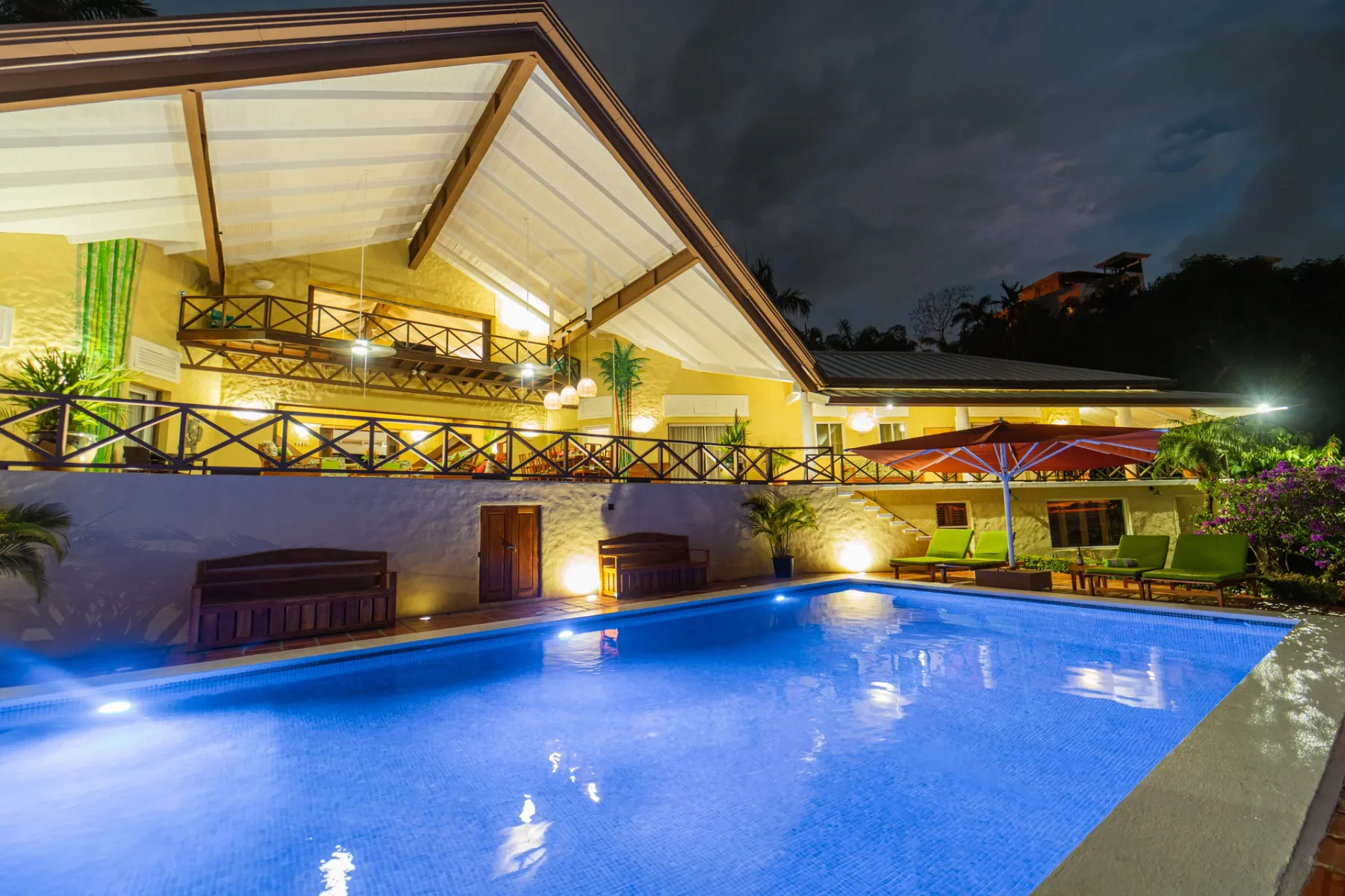 Una piscina iluminada junto a un patio cubierto por la noche.