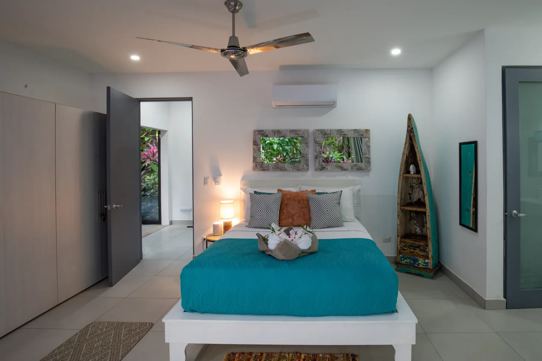 Un dormitorio con una cama cubierta de turquesa y obras de arte en la pared.