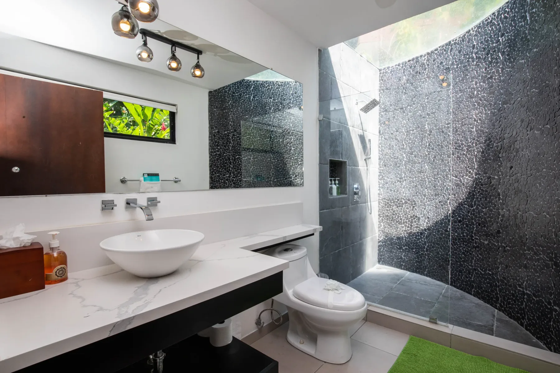 Un baño moderno con un tocador blanco y una ducha a ras de suelo.