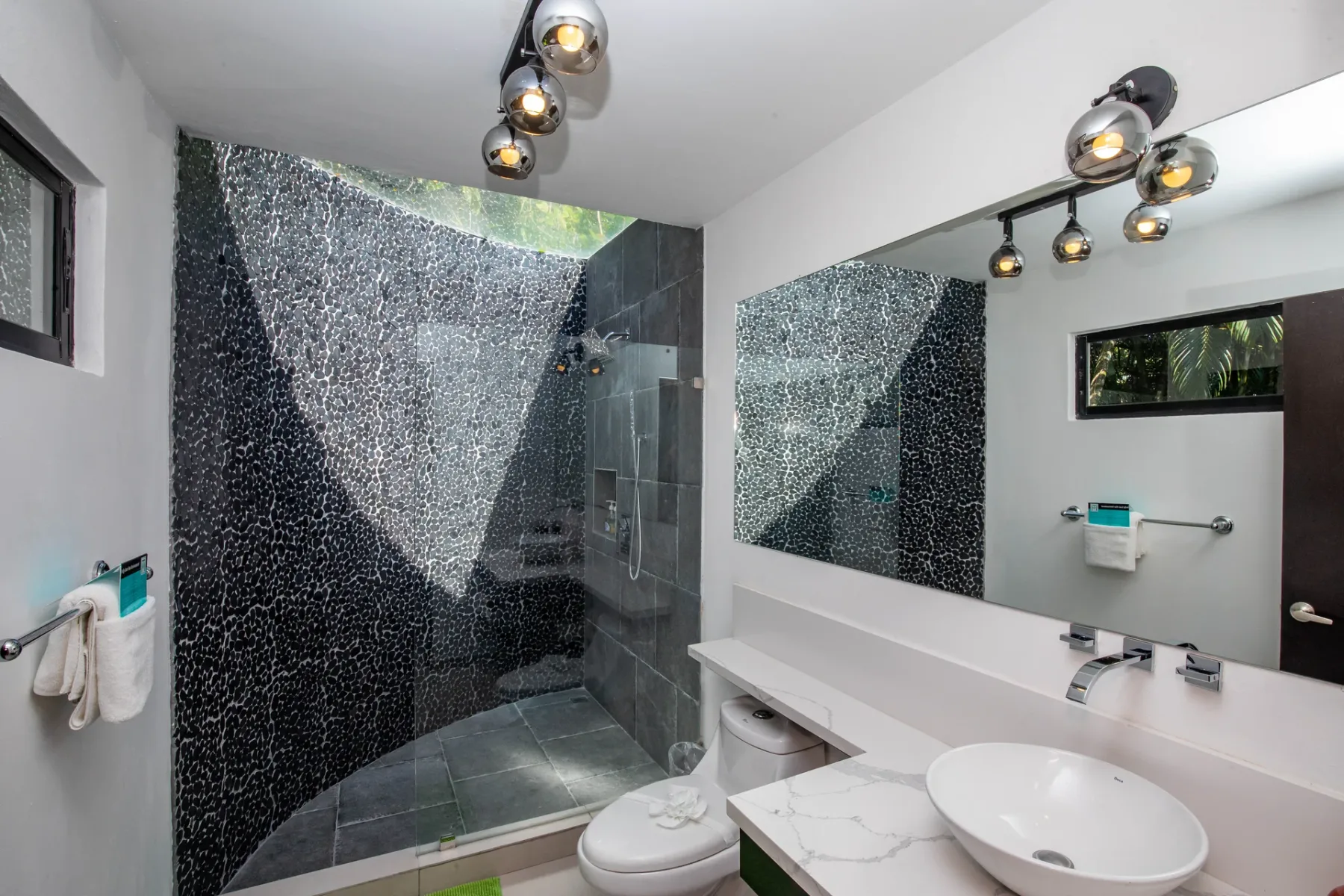 Un baño moderno con ducha de vidrio, espejo de pared y lavabo.