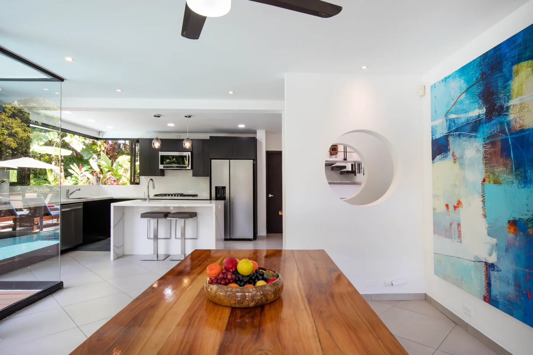 Cocina y comedor de concepto abierto, con una mesa de madera y arte colorido en la pared.