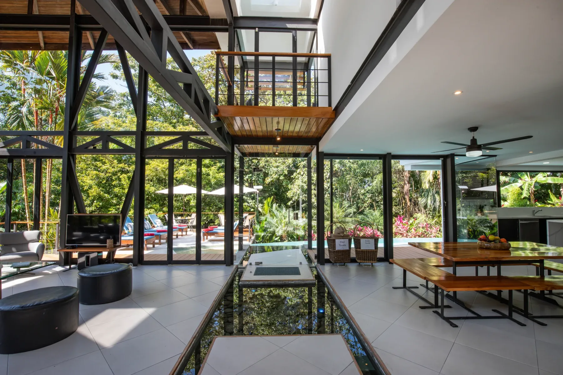 Sala y comedor de concepto abierto con ventanales de piso a techo y vistas a la vegetación.