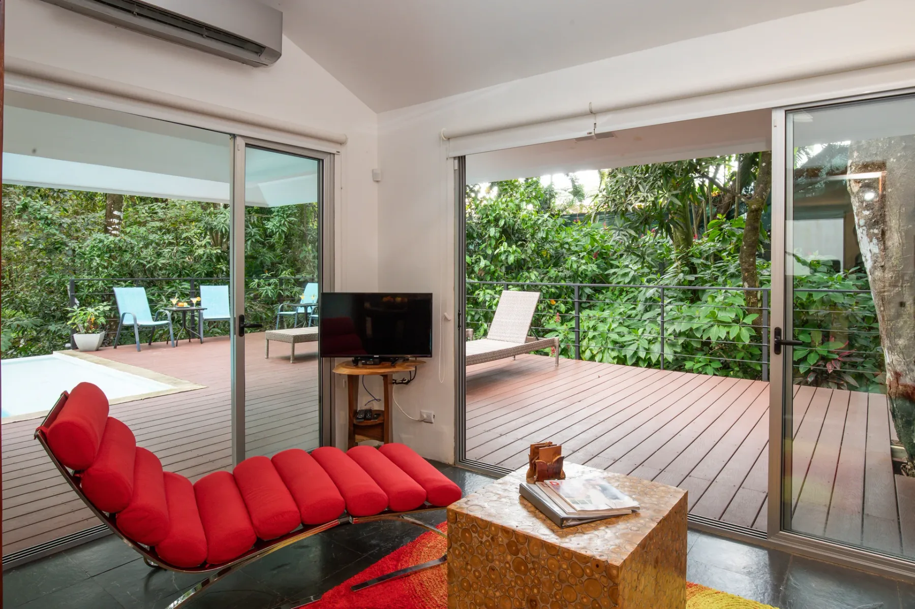 Una sala de estar se abre a una terraza rodeada de vegetación.