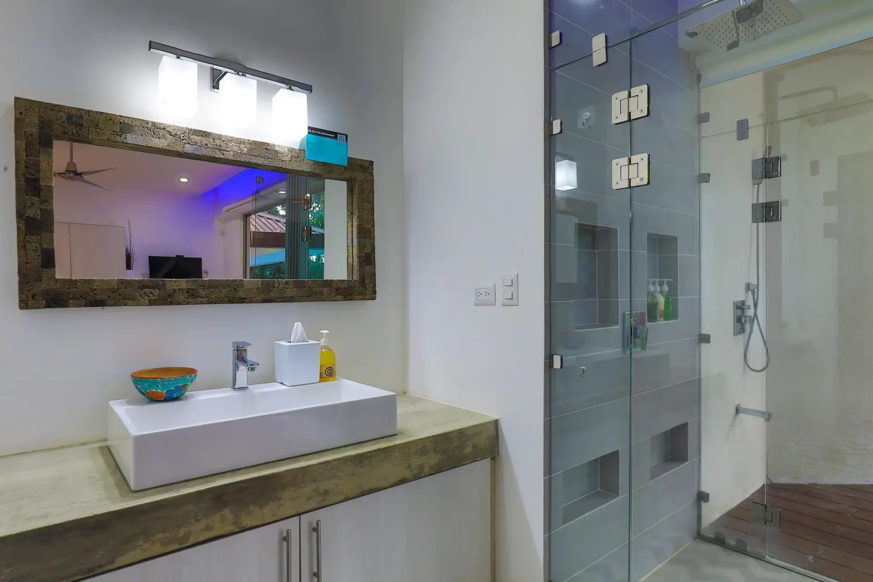 Se ve un lavabo de baño junto a una ducha de vidrio.