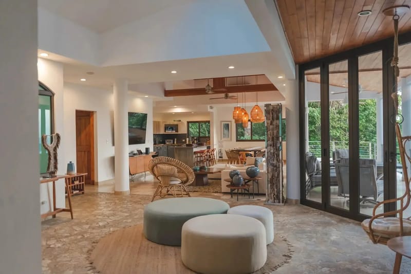 Casa Anjali Luxury Villa · 13. An open-plan living, dining, and kitchen area features vaulted teak ceilings and nine-foot folding glass walls that allow abundant natural light and direct views of the tropical rainforest, extending the living space onto a wraparound terrace.