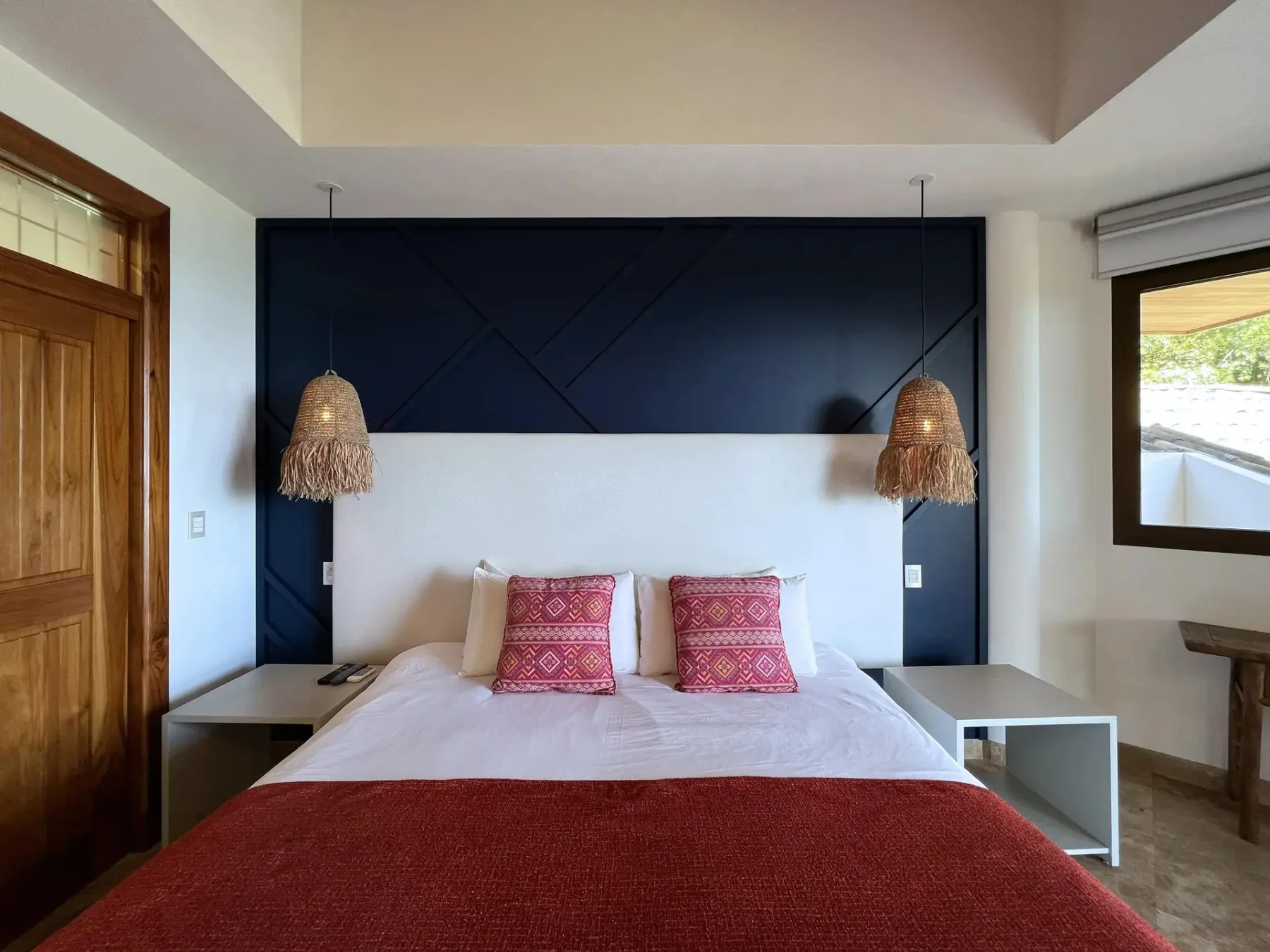 A bedroom with a bed against a dark geometric accent wall and a wooden door.