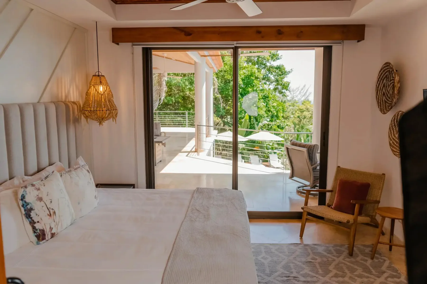 A bedroom with a bed and seating opens through glass doors to a terrace.