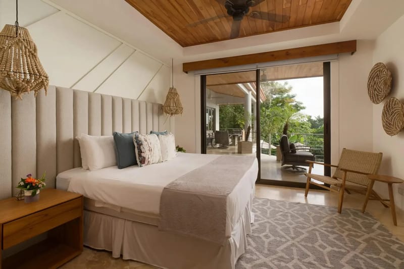 Casa Anjali Luxury Villa · 58. This king bedroom features a vaulted teak ceiling with a fan, a padded headboard, and floor-to-ceiling glass doors that open to a private terrace with rainforest views.
