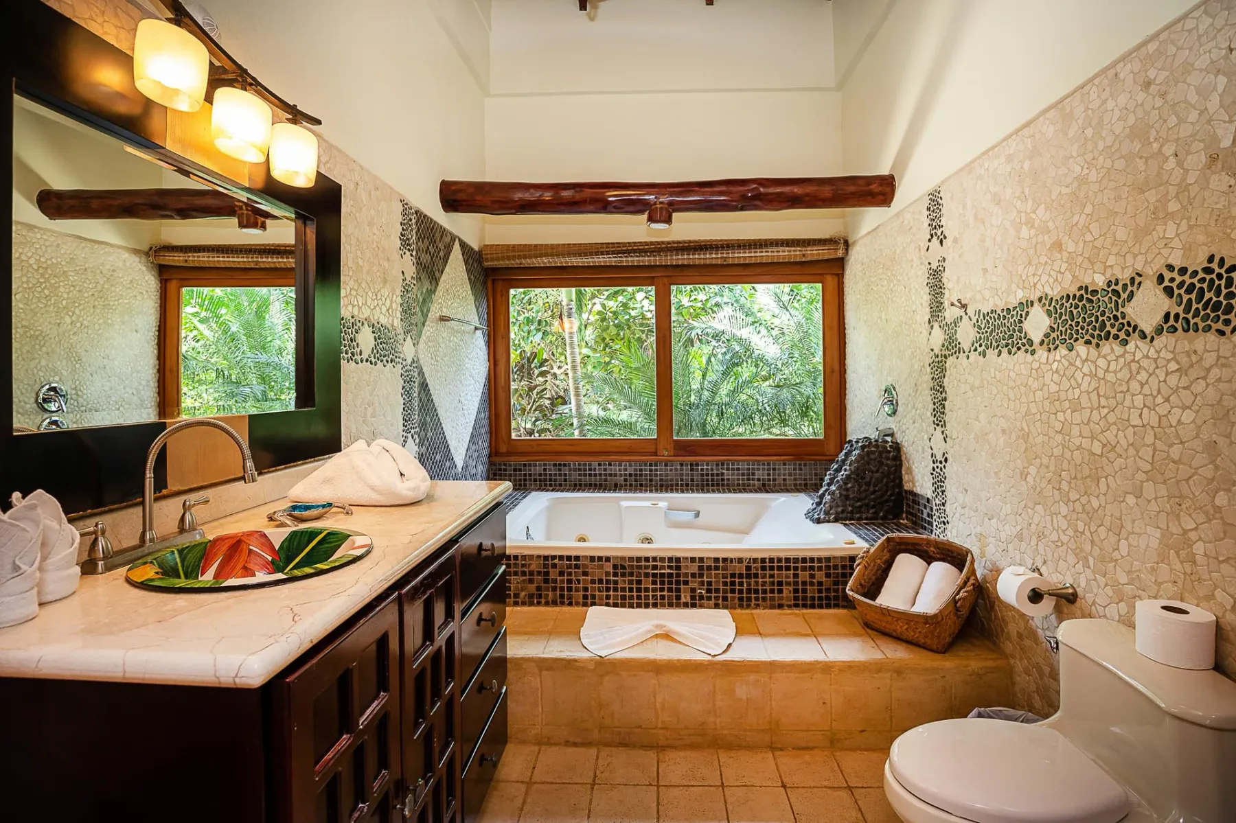 A bathroom with a bathtub beneath a wide window and a vanity along one wall.