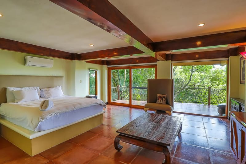 Casa Estrella del Mar · 41. This bedroom features a large bed, exposed wooden ceiling beams, and sliding glass doors opening to a terrace that provides extensive rainforest views and natural light.