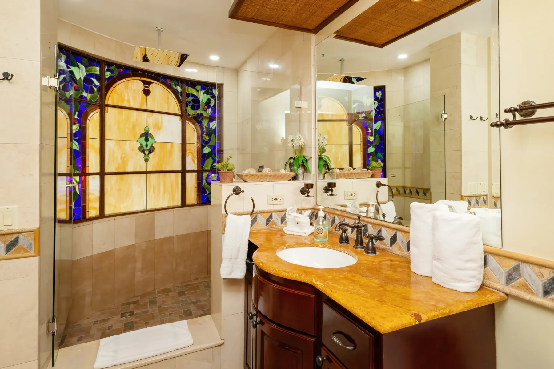 A bathroom with a large vanity, mirrors, and a decorative stained-glass window.