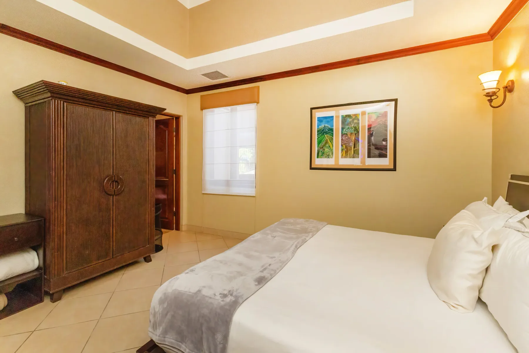 A bedroom with a large bed, a wooden wardrobe, and a window.