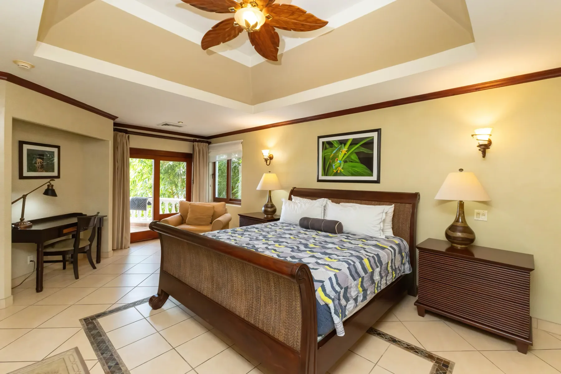 A bedroom with a large bed, bedside tables, and a ceiling fan.