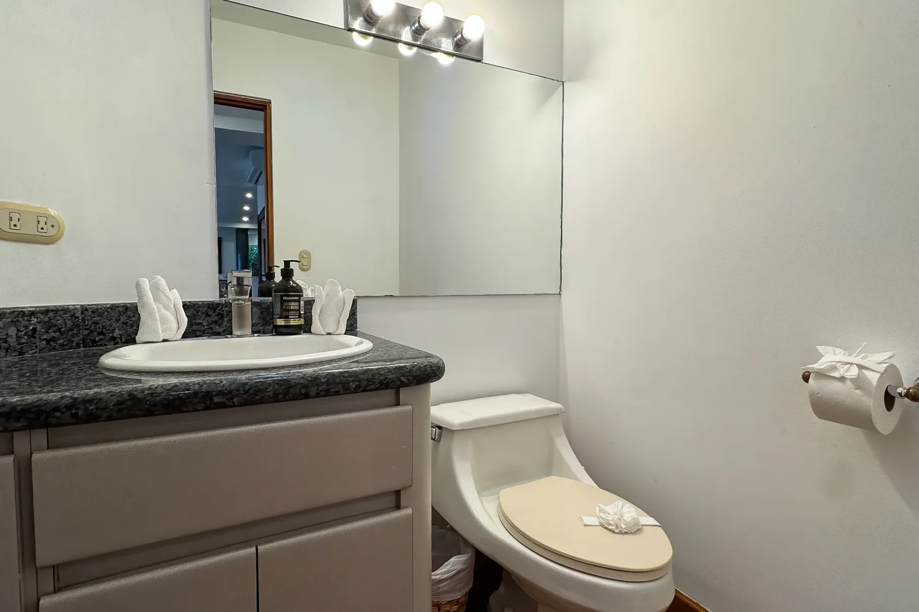 A bathroom with a sink vanity, mirror, and toilet.