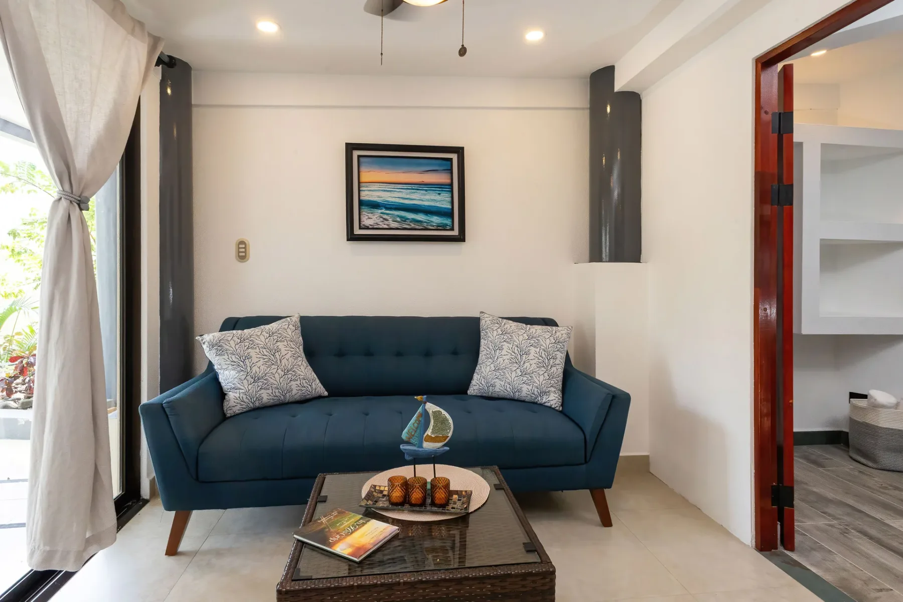 A living room with a dark blue sofa, coffee table, and framed wall art.
