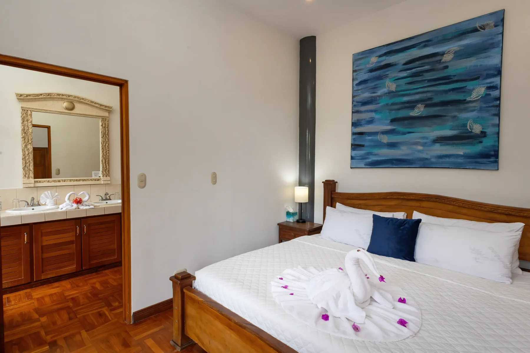 A bedroom with a wooden bed, white bedding, and blue ocean-themed wall art.