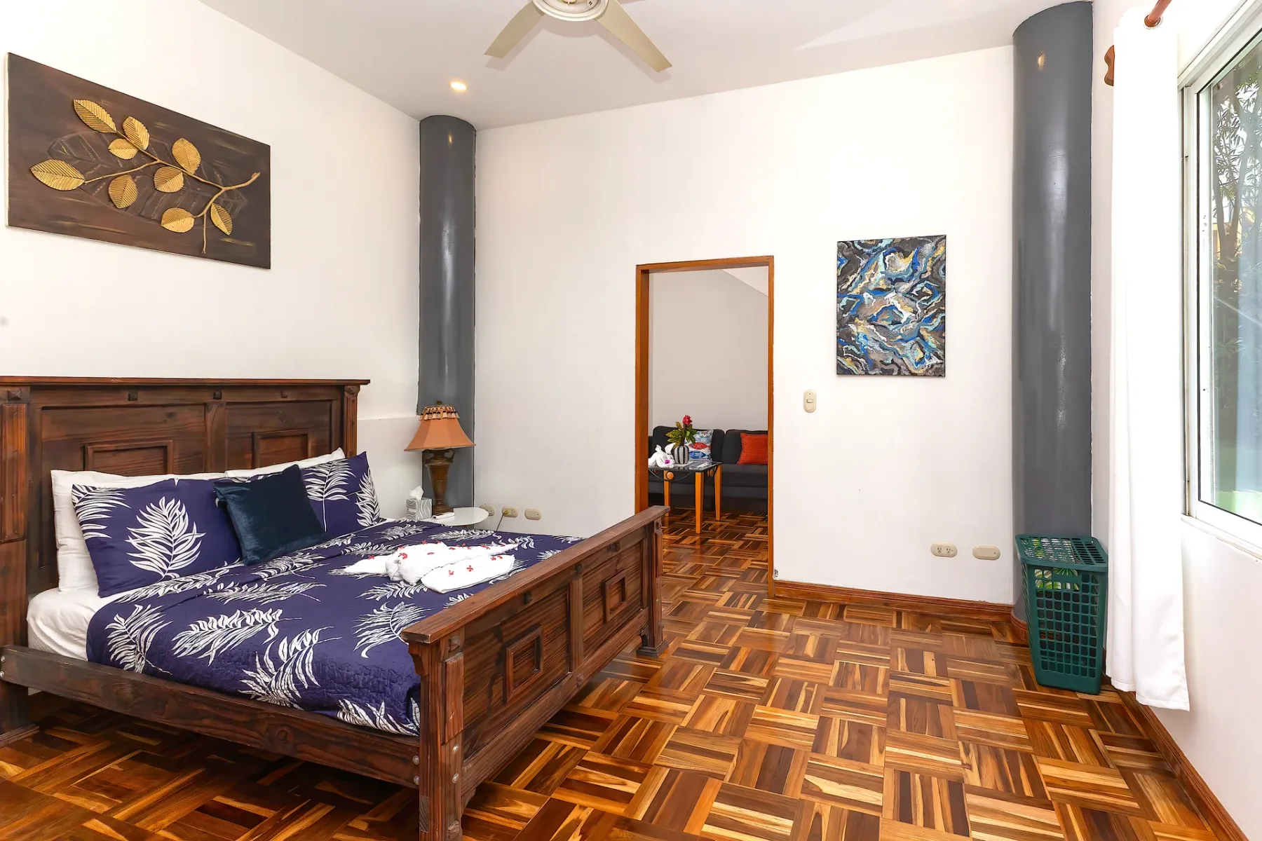 A bedroom with a wooden bed, patterned bedding, and parquet flooring.
