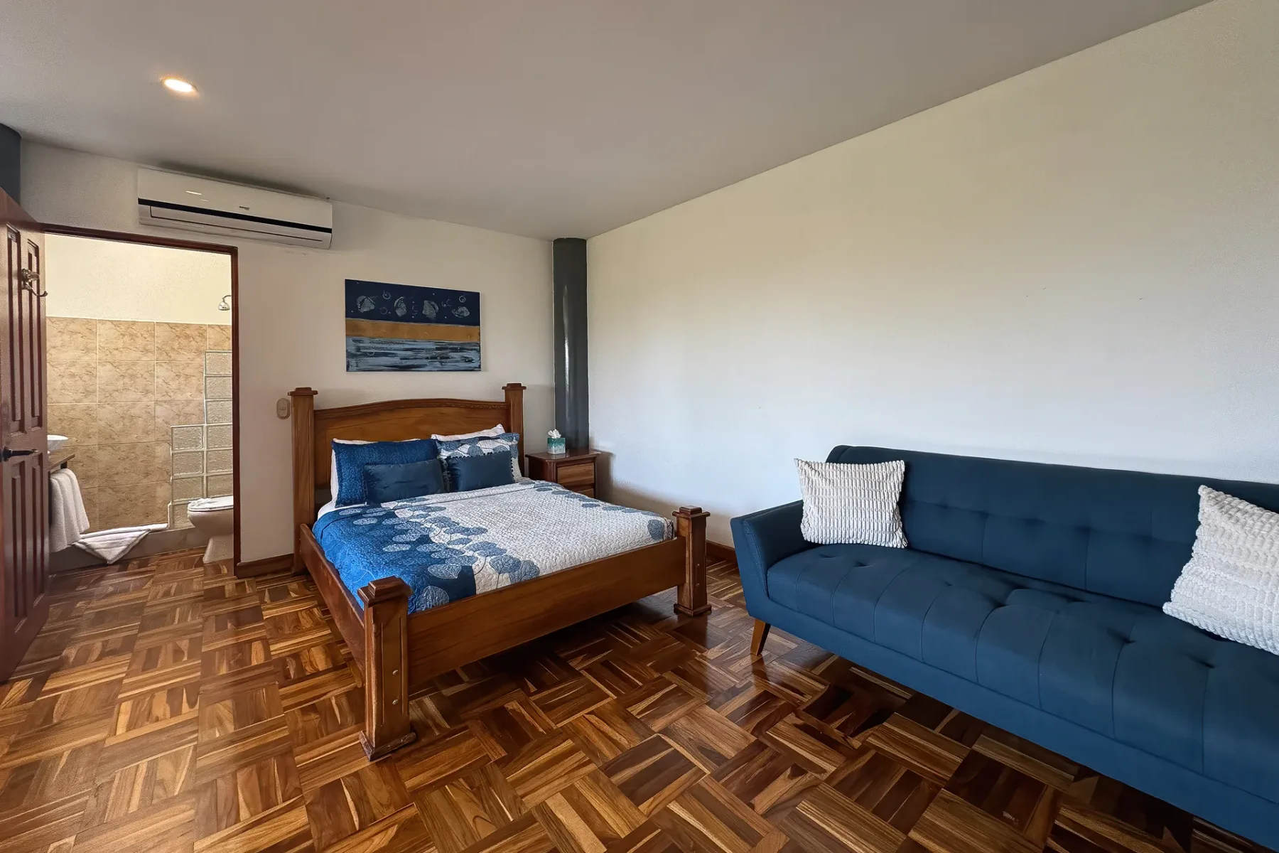 A bedroom with a wooden bed and a blue sofa.