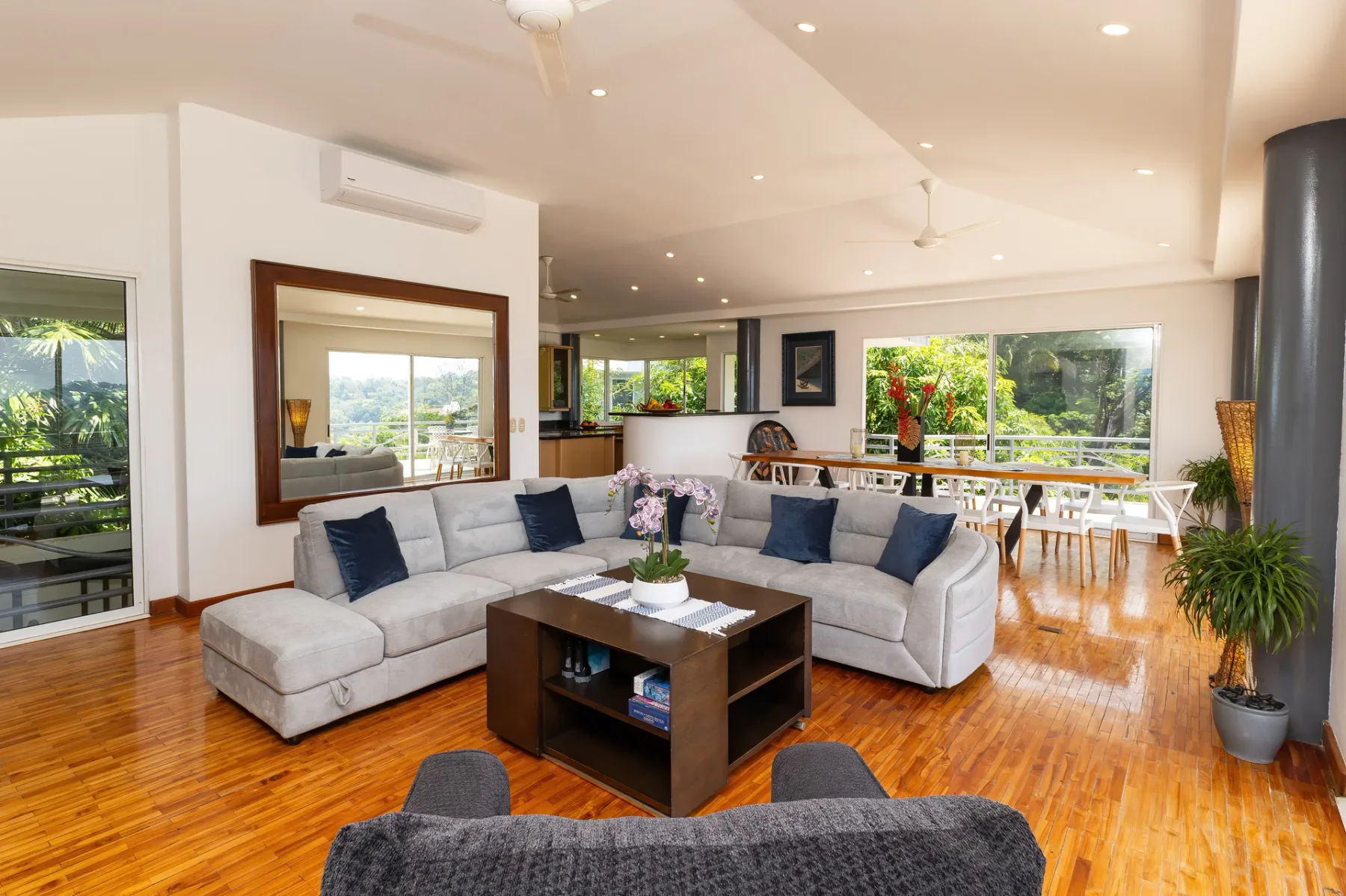 A bright living room with sectional seating and a dining area by the windows.