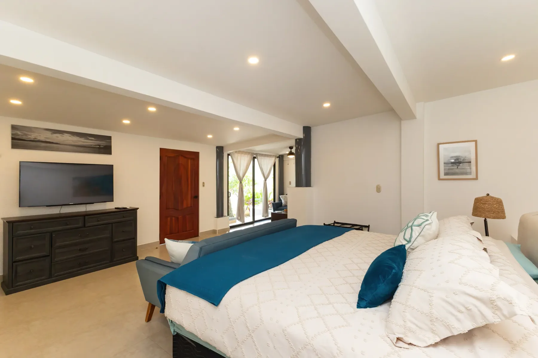 A bedroom with a large bed, a television, and glass doors opening to a patio.